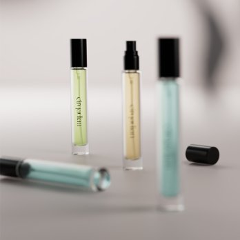 Three clear glass Cirqadian fragrance bottles with black caps are arranged on a soft gray surface. One bottle lies horizontally in the foreground, while two stand upright in the background.