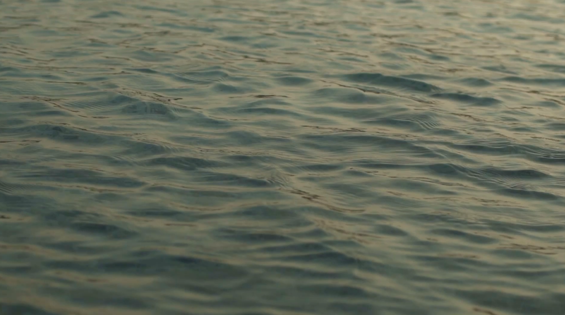 Close-up of rippling teal ocean water catching golden evening light
