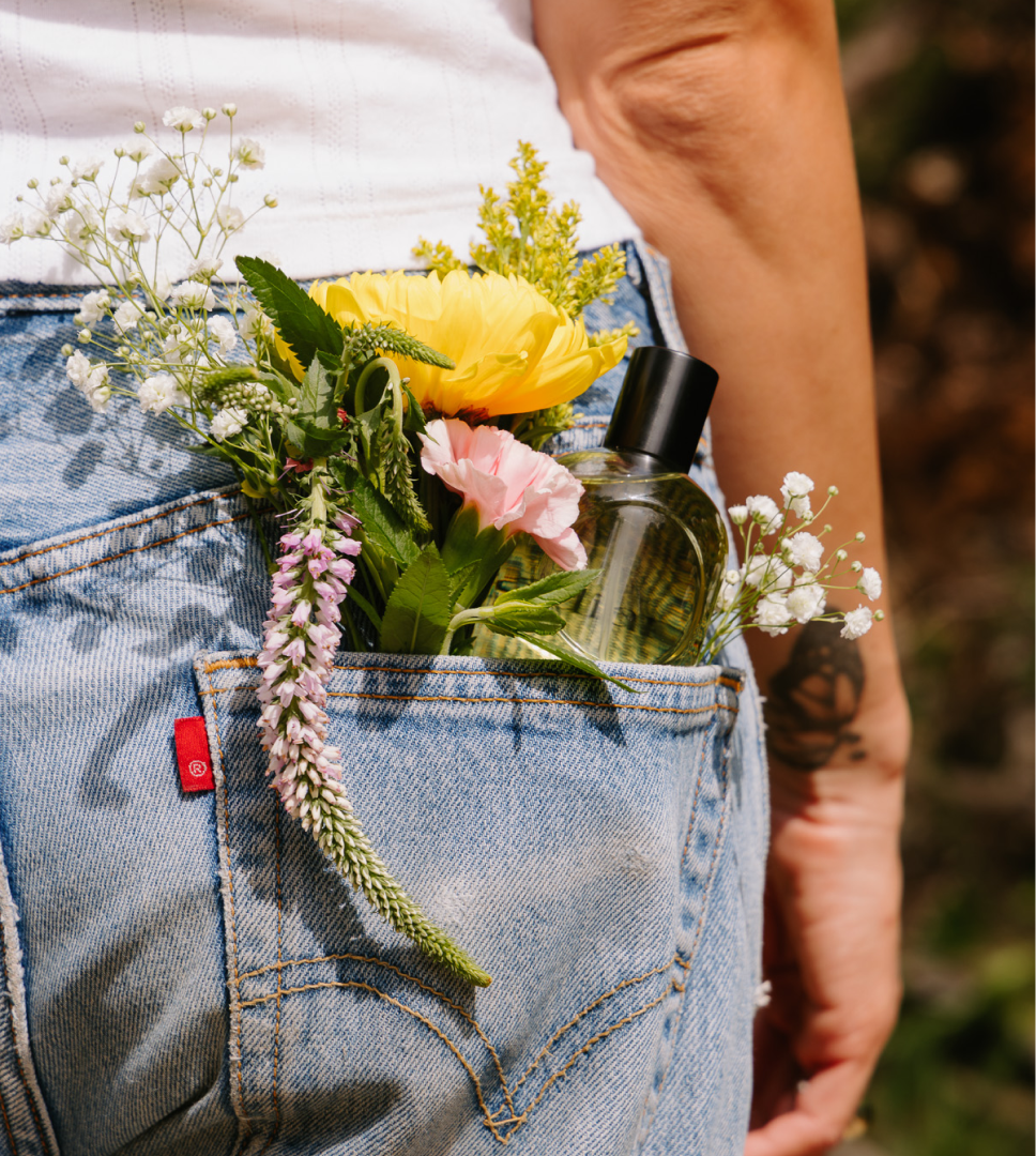 Wildflowers and a Cirqadian fragrance bottle tucked into the back pocket of blue jeans

