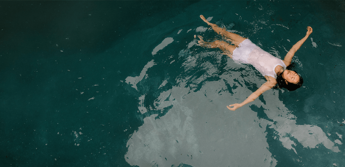 Person floating in a pool with a world map reflection