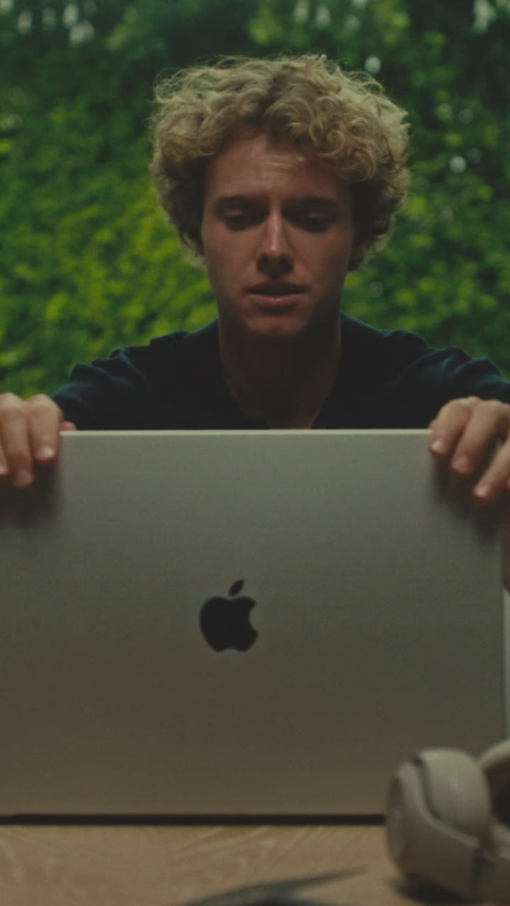 Curly-haired young man outdoors closing a laptop amid greenery, video thumbnail